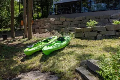 two kayaks sitting on the grass in a yard at 4Bdrm Muskoka Retreat, Fire Table, Games, Netflix in Port Carling