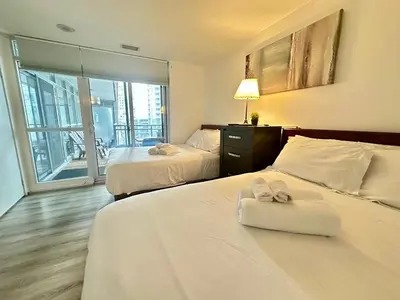 a hotel room with two beds and a balcony at Corner suite Courtyard view 4 real beds in Toronto
