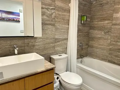 a bathroom with a toilet and a sink and a tub at Corner suite Courtyard view 4 real beds in Toronto