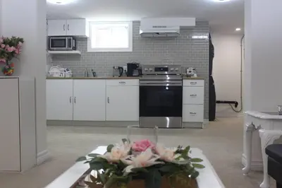 a kitchen with white cabinets and a table with flowers at Exclusive Private Basement in London