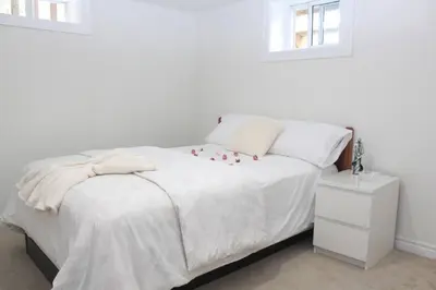 a bedroom with a white bed with red flowers on it at Exclusive Private Basement in London