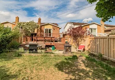 a house with a fence and a backyard with a grill at Home away from home in Brampton