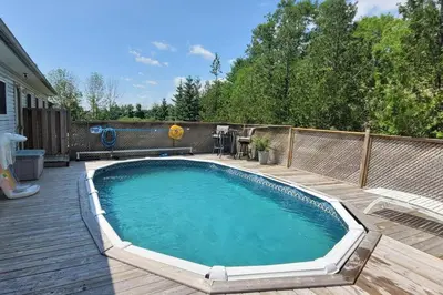 a large swimming pool on a wooden deck next to a backyard at Summer Getaway with Pool and Nearby Attractions in Cobourg