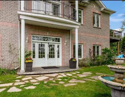 a brick house with a white door and a balcony at Summer Getaway with Pool and Nearby Attractions in Cobourg