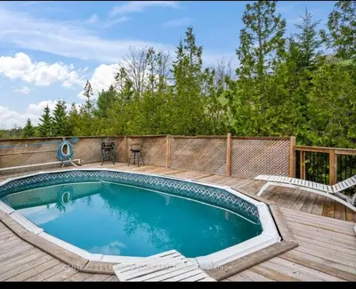 a large swimming pool on a wooden deck with a fence at Summer Getaway with Pool and Nearby Attractions in Cobourg