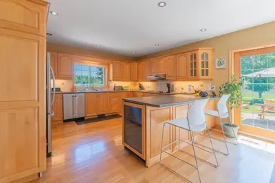 a kitchen with wooden cabinets and a island with bar stools at Luxury Hillside Farmhouse on The Bay of Quinte in Belleville