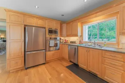 a kitchen with wooden cabinets and stainless steel appliances at Luxury Hillside Farmhouse on The Bay of Quinte in Belleville