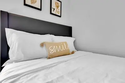 a large white bed with a pillow on it at Cozy 3BR Home with Parking Near Kitchener Attractions in Kitchener