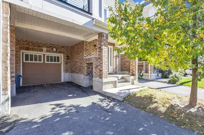 a brick house with a garage and a tree at Cozy 3BR Home with Parking Near Kitchener Attractions in Kitchener