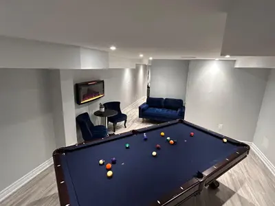 a pool table in a living room with a room with a pool table at Ravine Retreat - 3RM Suite, 2BD, 1 WR, Pool, Sauna in Whitby
