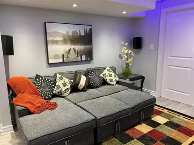 a living room with a couch with pillows on it at Ravine Retreat - 3RM Suite, 2BD, 1 WR, Pool, Sauna in Whitby