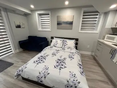a bedroom with a bed and a blue chair at Ravine Retreat - 3RM Suite, 2BD, 1 WR, Pool, Sauna in Whitby
