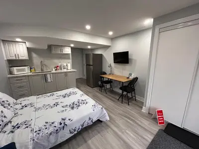 a bedroom with a bed and a kitchen with a table at Ravine Retreat - 3RM Suite, 2BD, 1 WR, Pool, Sauna in Whitby
