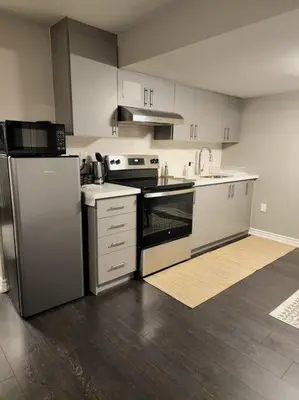 a kitchen with stainless steel appliances and wooden floors at 1 Bedroom basement apartment with separate entrance in Milton