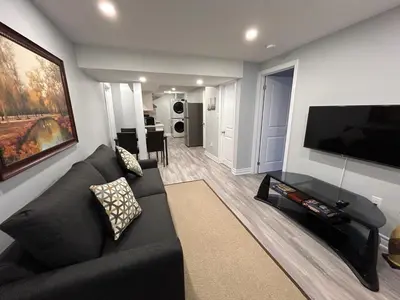 a living room with a black couch and a flat screen tv at Rita's Kunjo - 2BR, 3BD, 2WR, Full Ktchn, Living in Whitby