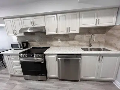 a kitchen with white cabinets and a stove and a sink at Rita's Kunjo - 2BR, 3BD, 2WR, Full Ktchn, Living in Whitby