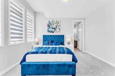 a blue bed in a white room with windows at Executive Brand New House 5 Bedrooms and Office in Cambridge