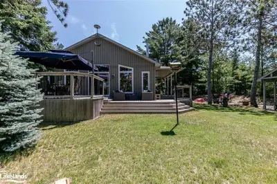 a house with an umbrella in the yard at Cozy cottage on a private beach -Georgian Bay in Tiny