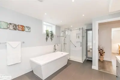 a white bathroom with a tub and a shower at Cozy cottage on a private beach -Georgian Bay in Tiny