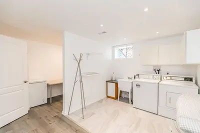 a white kitchen with white appliances and a table at Cozy cottage on a private beach -Georgian Bay in Tiny