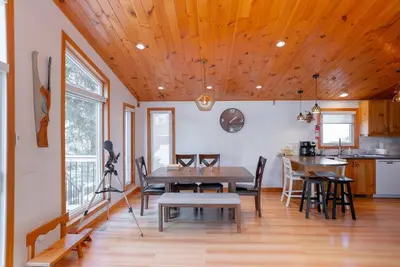 a dining room with a wooden ceiling and a table at Cozy cottage on a private beach -Georgian Bay in Tiny