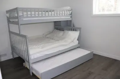 a white bunk room with two bunk beds at Cozy cottage on a private beach -Georgian Bay in Tiny