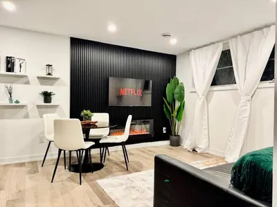 a living room with a table and chairs and a tv at Luxury Stay Near Niagara Falls in Niagara Falls
