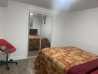 a bedroom with a bed and a mirror and a chair at 2 Bedroom Guest Apartment with Separate Entrance in Brampton