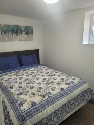 a bed in a bedroom with a blue and white blanket at 2 Bedroom Guest Apartment with Separate Entrance in Brampton