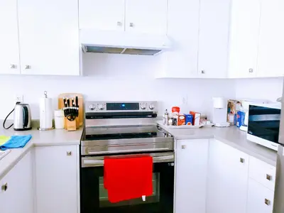 a kitchen with white cabinets and a red chair at New 3-BR Home Near Niagara Falls with King Bed 75 Inch TV and Free Parking in Thorold