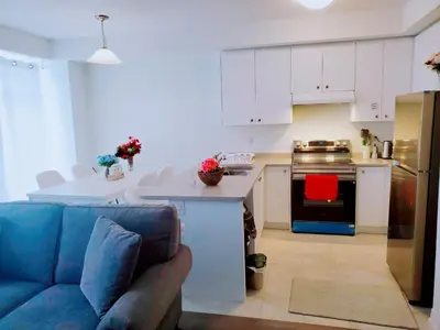 a kitchen with white cabinets and a blue couch at New 3-BR Home Near Niagara Falls with King Bed 75 Inch TV and Free Parking in Thorold
