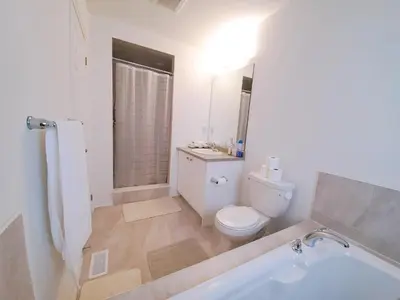 a white bathroom with a toilet and a tub at New 3-BR Home Near Niagara Falls with King Bed 75 Inch TV and Free Parking in Thorold