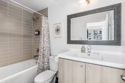 a bathroom with a sink and a toilet and a mirror at Stylish 2BR Urban Escape, BBQ, Private Terrace in Toronto