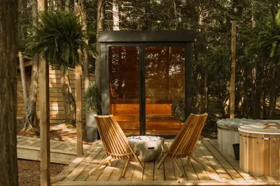 two chairs on a wooden deck with a cabin at Aux Box Muskoka Modern Muskoka Bunkie in Huntsville