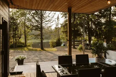 a patio with a table and chairs and a view of a lake at Wolegib Waterfront Retreat in Muskoka in Huntsville