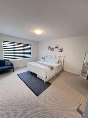 a white bedroom with a bed and a window at Brand New Luxurious 4B Townhouse in Oshawa