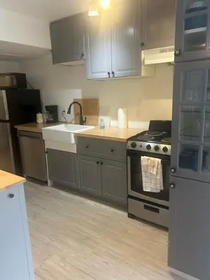 a kitchen with gray cabinets and a stove and a sink at Treetop Suite in Haliburton
