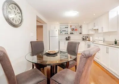 a kitchen with a glass table and chairs and a clock at 2 bedroom apartment-2 free parking -14 min to Pearson airport in Mississauga