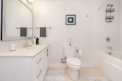 a white bathroom with a toilet and a tub and a sink at 2 bedroom apartment-2 free parking -14 min to Pearson airport in Mississauga