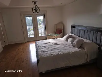 a bedroom with a large bed and a chandelier at Chez Mason in Richmond Hill