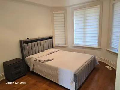 a bedroom with a bed and two windows at Chez Mason in Richmond Hill