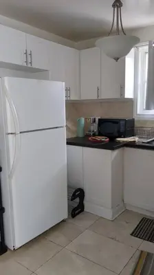 a white kitchen with a black counter and a white refrigerator at Whole House Fair Price Great Amenities in Richmond Hill