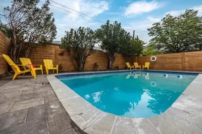 a swimming pool with yellow chairs and a fence at Modern Master Suite Private Ensuite 29 Nights in Toronto