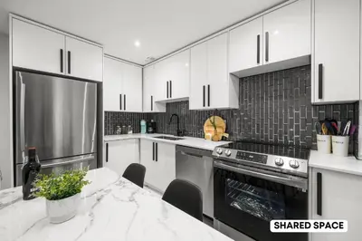 a kitchen with white cabinets and a table and a refrigerator at Modern Master Suite Private Ensuite 29 Nights in Toronto