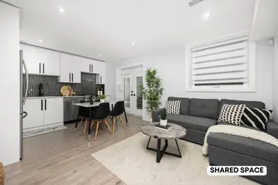 a living room with a couch and a table and a kitchen at Modern Master Suite Private Ensuite 29 Nights in Toronto