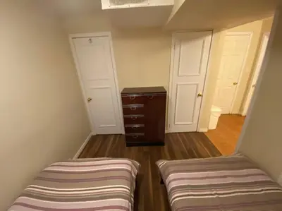 an attic room with two beds and a dresser at Sunnys Home Stays 1 Bedroom Bath & Kitchenette Toronto Mississauga At Erin Mills With Pvt Entrance in Mississauga