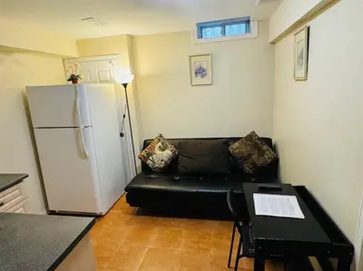 a living room with a black couch and a refrigerator at Sunnys Home Stays 1 Bedroom Bath & Kitchenette Toronto Mississauga At Erin Mills With Pvt Entrance in Mississauga