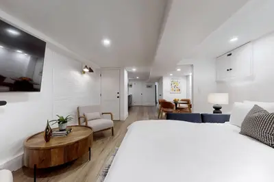 a bedroom with a large white bed and a living room at Fresh and Modern Guest Suite in Toronto