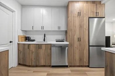 a kitchen with white cabinets and a stainless steel refrigerator at Private House with parking & steps to subway in Toronto