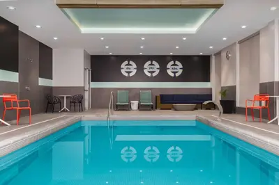 a pool in a hotel room with red chairs and a pool at Tru By Hilton Bracebridge, On in Bracebridge